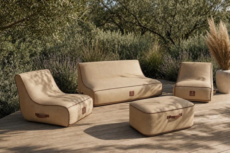 Un salon de jardin gonflable complet beige avec liseré marron, comprenant un canapé deux places, deux fauteuils et un pouf, installé sur une terrasse en bois entourée de végétation méditerranéenne.