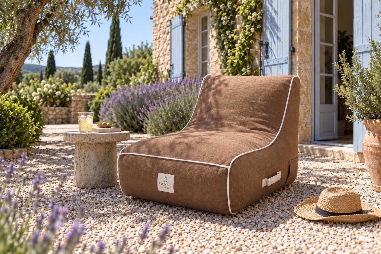 Fauteuil marron dans la cour en gravier d'une maison provençale avec lavande et volets bleus